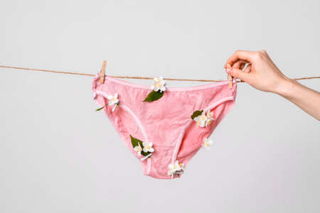 Woman hangs underwear with flowers on clothesline, concept content for feminist blog, poster about womens healthの写真素材