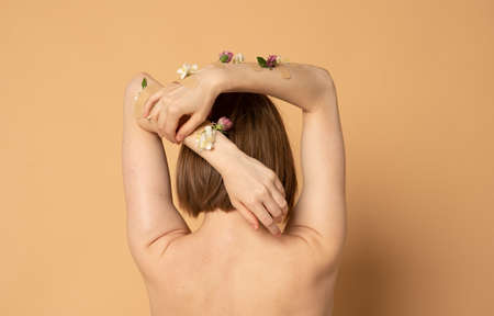 Back of pretty woman with hands with flowers and patches, concept photo for feminist or beauty blogの写真素材