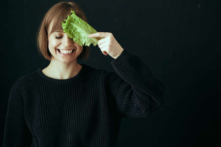 A young happy girl food blogger cooks healthy food in the kitchen and laughs playfully.の写真素材