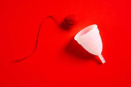 Menstrual cup and a red ball isolated on a red background, concept photography for womens or feminist blogの写真素材