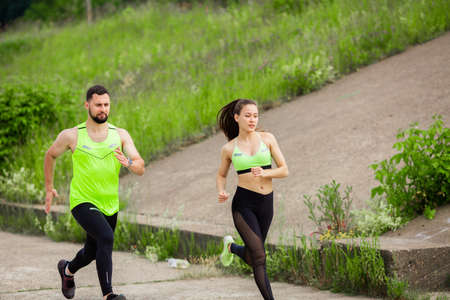 Athletic girl and man in stylish sportswear run in nature, photo for blog and ad of sport and healthy lifestyleの写真素材