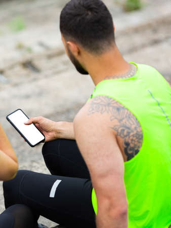 Athletic man in stylish sportswear train with phone with empty screen, photography for sport blog or appの写真素材