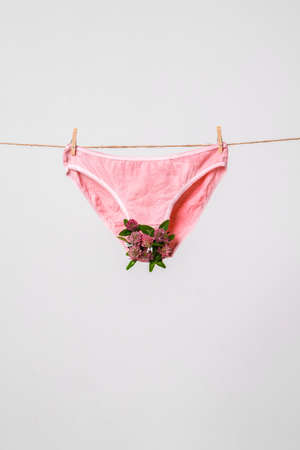 Womans pink underwear with flowers on clothesline, concept content for feminist blog, poster about womens healthの写真素材