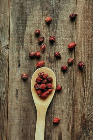 Rosehip in a wooden spoon on wooden table. Close up photography for food blog or poster . High quality photoの写真素材