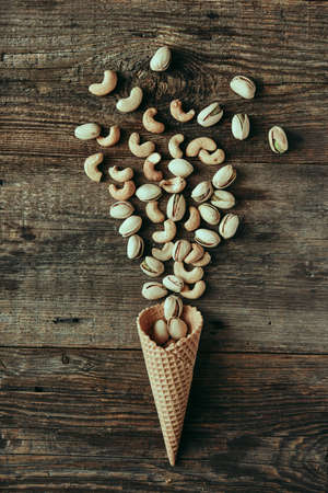 Pistachios in waffle cone on wooden table, healthy snack, concept flat lay photography and content for food blog. High quality photoの写真素材