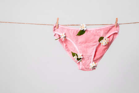 Womans pink underwear with flowers on clothesline, concept content for feminist blog, poster about...