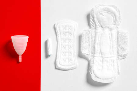 Menstrual cup white eco friendly reusable silicone, pads and tampons isolated on a red and white backgroundの写真素材
