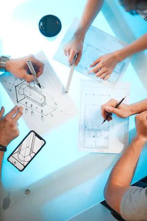 Team of architects discussing project at modern office, creative work place, top view on neon blue...