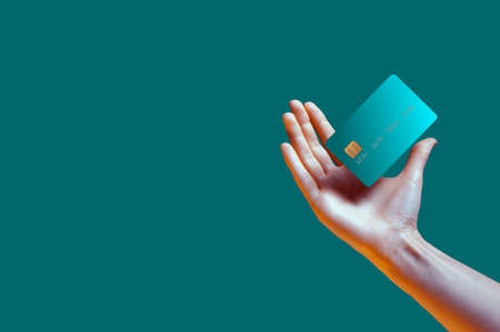 Close up female hand holds levitating template mockup Bank credit card with online service isolated on green backgroundの写真素材