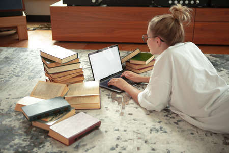 Cute teen girl student in casual cloth lying on floor with blank screen laptop, books. Back to...