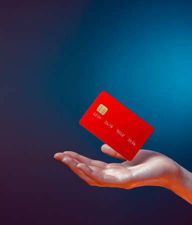 Close up female hand holds levitating template mockup Bank credit card with online service isolated on blue backgroundの写真素材
