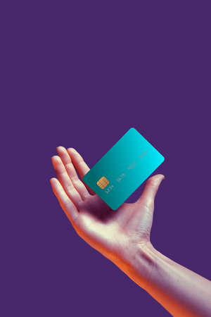 Close up female hand holds levitating template mockup Bank credit card with online service isolated on violet backgroundの写真素材