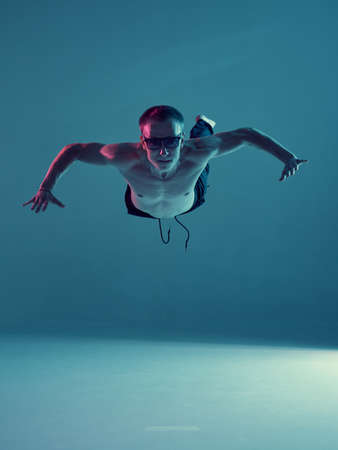 Boy dancing contemporary dance in studio without a t-shirt in neon light. Complex tricks....
