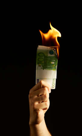 Burning money in Mans arm isolated on black background. Concept photo about protests, financial crisis and bankruptcyの写真素材