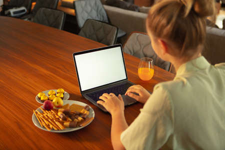 Teen girl blogger sitting at table with blank screen laptop. Close up photography for ad or blog,...