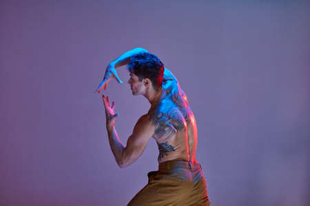 Cool young man dancer without shirt in neon light background in studio. Dance school poster. Body...