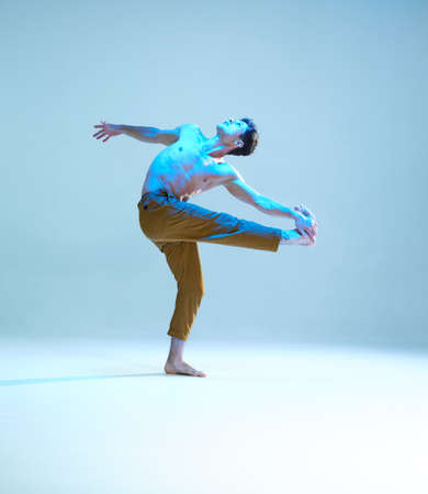 Cool flexible young man dancer dancing without shirt in neon blue light. Dance school poster. Dance...
