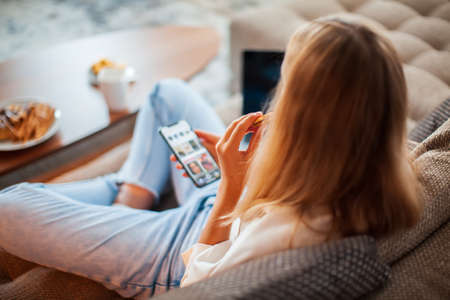 Young cute modern girl with smartphone sitting in the Lotus position and resting, top viewの写真素材