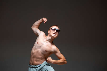 Crazy young guy breakdancer in sunglasses dancing hip-hop without shirt in studio. Dance school posterの写真素材