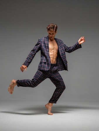 Stylish young man dancer in suit dancing modern dance with naked torso in studio. Dance school poster. Dance lessonsの写真素材