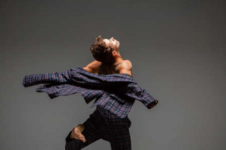 Stylish young guy dancer in suit dancing modern expressive dance in studio. Dance school poster. Dance lessonsの写真素材