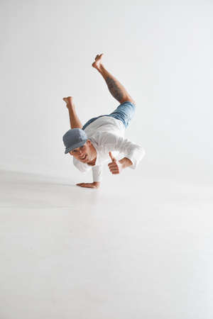 Cool smiling guy breakdancer dancing lower break dance shows thumbs up isolated on white background. Dance school posterの写真素材