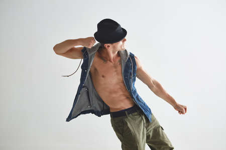 Cool young guy breakdancer in hat dancing hip-hop in studio isolated on white background. Dance...