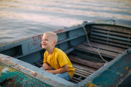Cool smiling baby boy sitting on boat on river in summertime, photography for travel blog or family blog or adの写真素材