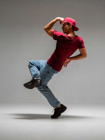 Guy dancing contemporary dance in studio isolated on gray background. Break dance lessons.の写真素材