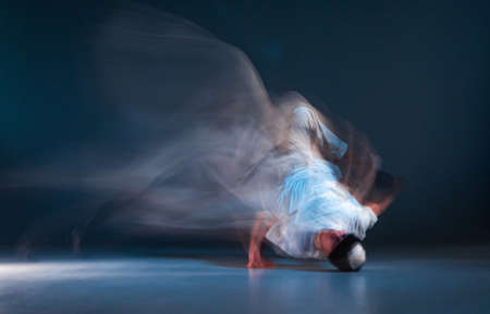 Stylish young guy breakdancer dancing hip-hop on the floor in neon light. Dance school poster. Long...