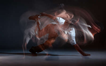 Guy breakdancer dancing hip-hop on the floor in studio on black background. Dance school poster. Long exposure shotの写真素材