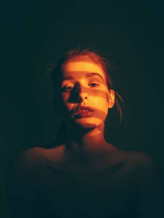 Pretty young girl with shadow pattern on face in studio on black background