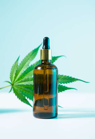Glass template jar with CBD cannabis product with hemp leaf in blue neon light, close upの写真素材