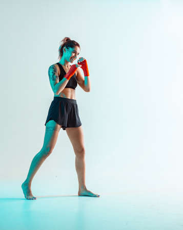 Athletic smiling girl in stylish sportswear posing in studio isolated in neon. Mixed martial arts posterの写真素材