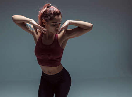 Portrait of a modern young girl performing elements of contemporary dance on a gray background.