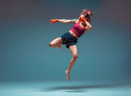A young female fighter performs a jump kick.の写真素材