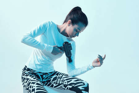 Percussion massager, sports young brunette female massaging hand in neon studio lightの写真素材