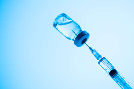Vial and syringe of vaccine, medicine in blue studio light, copy space. Vaccination immunization campaignの写真素材