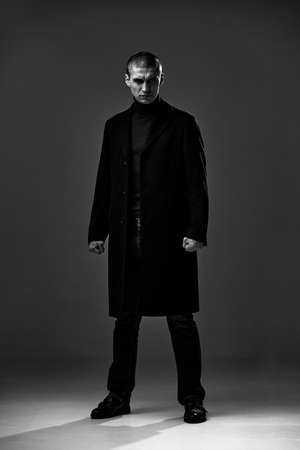 Confident serious frowning angry guy, detective or security on gray studio background,black and white male portraitの写真素材