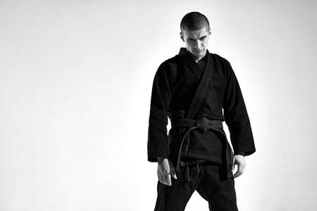 Confident frowning aggressive guy in kimono for mix fight on studio background with copy space, black and white portraitの写真素材
