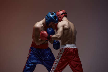 Wrestling of fighting athletic males boxers in studio, martial arts, mixed fight workoutの写真素材