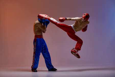 Sparring of fighting males boxers. Jumping male fighter kicking knockout competitor, martial arts, mixed fight conceptの写真素材