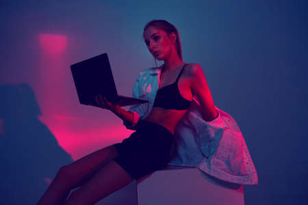 NFT cryptoart concept. Young girl create project on laptop for sale at a cryptocurrency token auction. Neon lightの写真素材