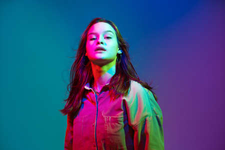 Cool young confident girl with long healthy hair posing in colorful neon studio light. Modern woman beauty portraitの写真素材