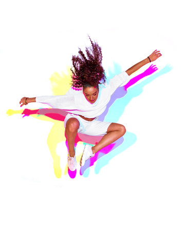 Jumping stylish mixed race young girl on white background. Rainbow colourful studio light. Fiery hip...