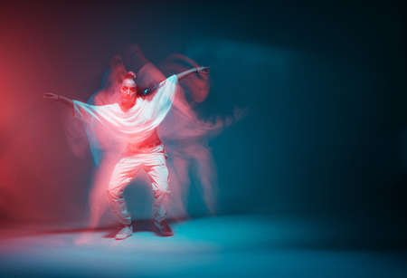 Contemporary hip hop dance. Cool dancing modern girl moving in colorful neon studio light. Long...