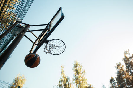 Basketball court on nature. Ball throwed into basketball hoop on summer sky background. Aiming, goal conceptの写真素材