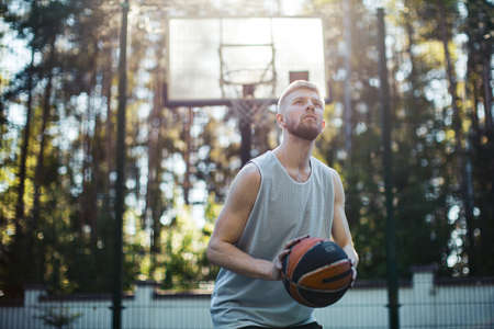 Professional handsome male american basketball player exercising on court outdoors in summer in sunlightの写真素材