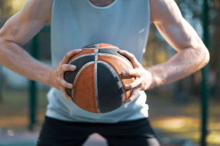 Professional basketball player holding ball, aiming before throwing, close-up advertising sportive photoの写真素材