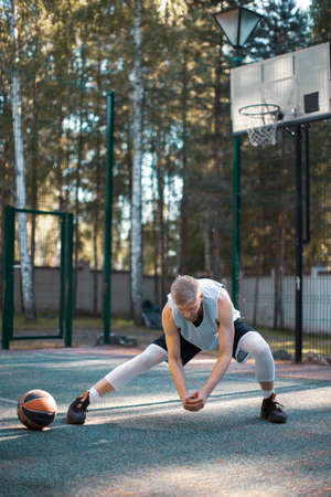 Professional male american basketball player training, warming up on court outdoors in summer....